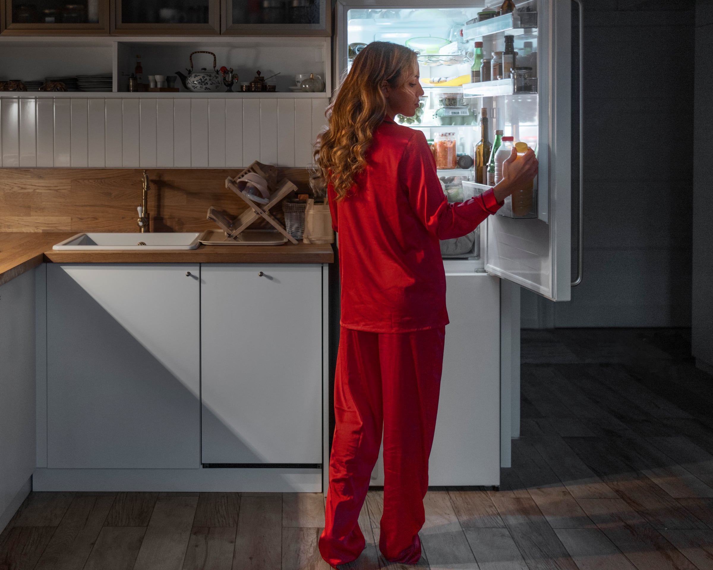 A resident checking a nearly empty fridge, late at night